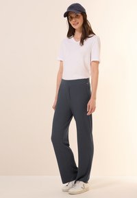 Casual witte v-hals t-shirt, grijze geribde wijde broek en witte sneakers. Geaccentueerd met een marineblauw pet en een relaxed fit. Simpel en comfortabel.