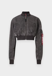 Cropped bomber jacket in black with a textured finish, zip closure, ribbed cuffs, and shoulder patches. Features a red tag on the sleeve.