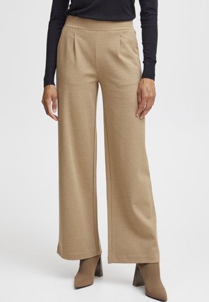 Beige weit geschnittene Hosen mit glatter Textur, plissierter Vorderseite, hoher Taille und klaren Linien, kombiniert mit Schuhen mit Absatz in einer passenden Farbe.
