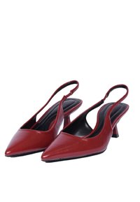 Scarpe slingback in cuoio rosso con punta affusolata, tacco basso e finitura liscia. Presentano un taglio curvo sul retro per un design aperto.