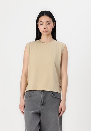 Beige, sleeveless top with a round neck, made of soft material. Features a relaxed fit and a straight hem. Paired with gray wide-leg pants.