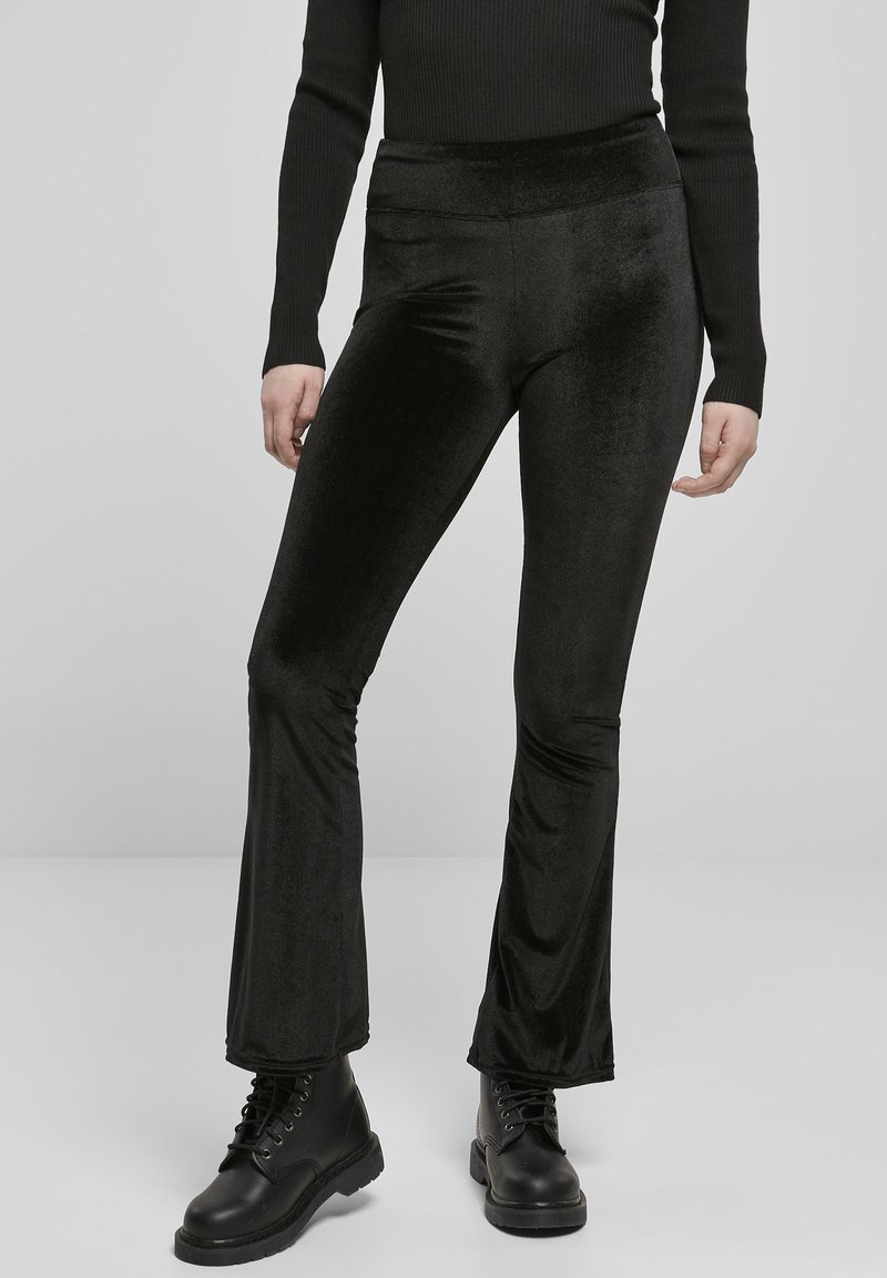 Svart, utsvakt leggings laget av myk, elastisk Stoff med en jevn tekstur. Bært med svarte ankelstøvler, har de en høy midje.