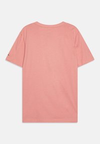 Camiseta de manga corta de color rosa claro con cuello redondo, que presenta una textura de algodón suave y un logotipo sutil en la manga izquierda.