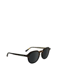 Occhiali da sole Calvin Klein con montatura in acetato tartarugato marrone, forma rotonda, lenti nere e dettaglio in metallo argento sulla tempia.