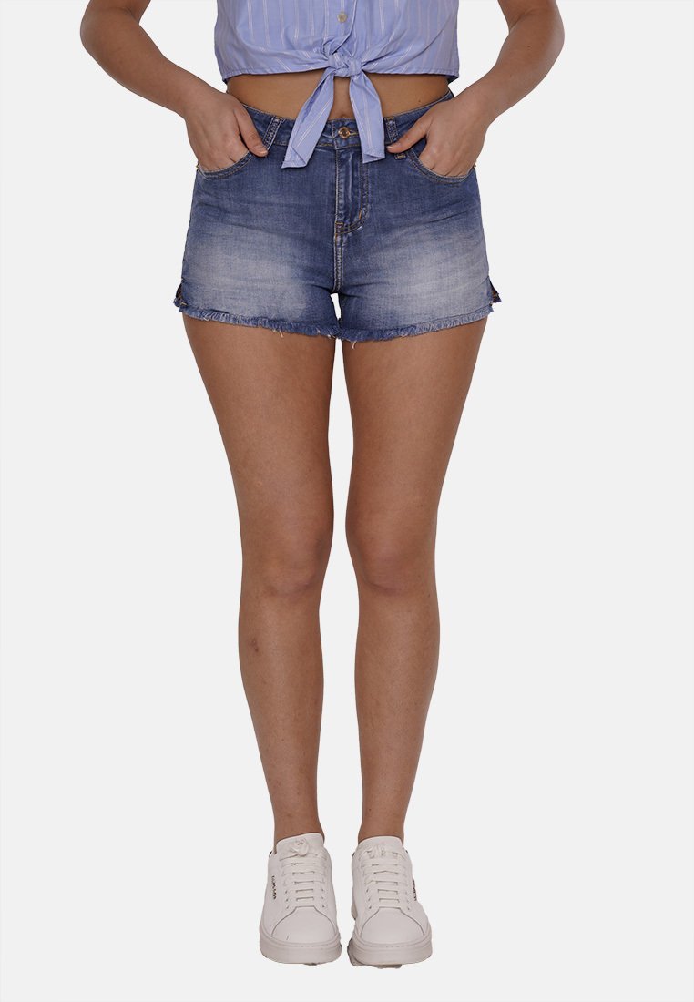 Shorts in denim con una tonalità azzurra chiara, con orlo sfilacciato e design a cinque tasche, abbinati a sneakers bianche.
