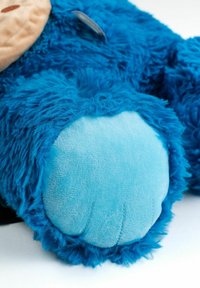 Close-up of blue furry plush toy paw with light blue padded pad and stitched details on white background.