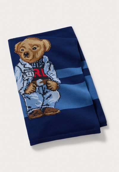 Knit scarf featuring a bear in a light blue outfit adorned with a dark blue striped background. The scarf is primarily navy.