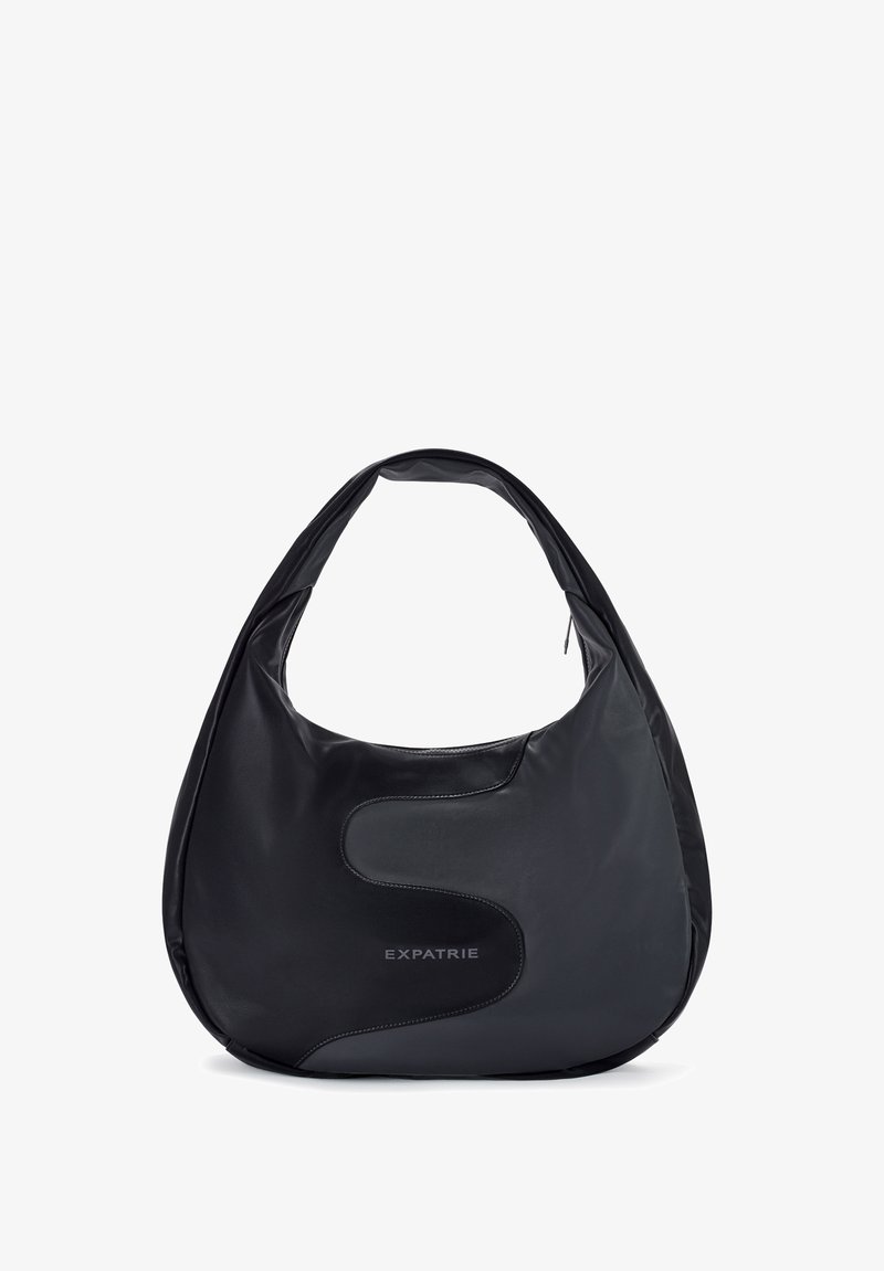 Čierna kožená ramenná taška s hladkou textúrou, zakriveným tvarom a výrazným šitým akcentom na boku. Obsahuje značku "EXPATRIE."
