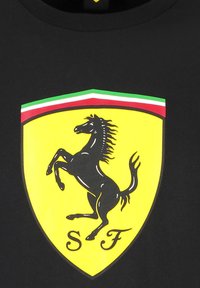 Czarna bawełniana koszulka z dużym żółtym logo Ferrari, przedstawiającym czarnego konia w ruchem, z zielonymi, białymi i czerwonymi paskami na górze.