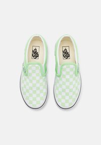 Grønn og hvit rutete slip-on sko med polstret krage og gummisåle, med en svart og hvit merket innersåle.