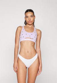 Reggiseno sportivo lilla con taglio, caratterizzato da una stampa ripetuta di panda e il logo K Karl Lagerfeld. Abbinato a un perizoma bianco a vita bassa.