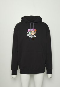 Sweat à capuche noir avec poche avant, personnages de dessins animés multicolores, texte violet « PUMA » et cordons bicolores présenté sur un mannequin blanc.