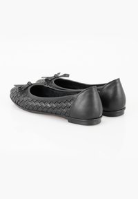 Schwarze Ballerinas mit einem geflochtenen Ledermuster, verziert mit einer Schleife auf der Vorderseite. Flache Sohlen und abgerundete Zehen. Glatte Textur und schlichte Form.
