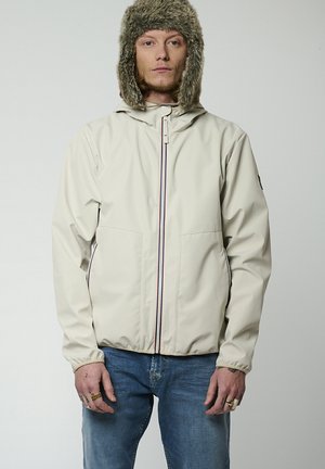Veste imperméable beige clair avec une fermeture éclair à l'avant, des rayures de couleur contrastée et deux poches latérales. Elle est dotée d'une capuche doublée en fausse fourrure.
