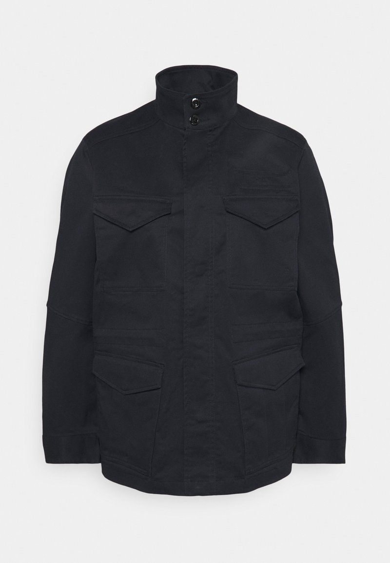 Navy blue coat featuring a high collar, four front pockets, and button details. Made of a sturdy fabric with a smooth texture.