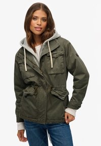 Khaki jakke med en grå hætte, justerbare snore i taljen og lommer med klap. Har lynlås- og trykknapslukning samt et afslappet design.