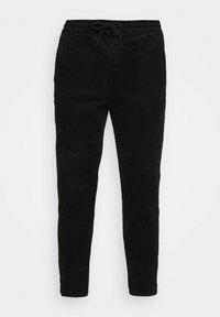 Zwarte corduroy broek met een tapse pasvorm, voorzien van een elastische tailleband en trekkoord, en met een verticale ribbelstructuur.