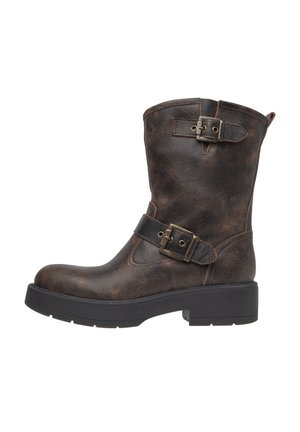 Bottine en cuir brun avec un bout rond, des boucles sur les côtés et une semelle épaisse noire. La texture vieillie rehausse le design robuste.