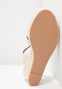 Sandalo a cuneo con tomaia beige texture, dettagli neri sulle cinghie e suola in gomma con motivo. Taglia contrassegnata come 37 sulla suola.