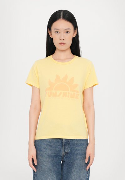 Gelbes Baumwoll-T-Shirt mit einer Sonnen-Grafik und dem Text "SUNSHINE STATE OF MIND" in einem sanften Orange-Ton. Kurze Ärmel und runder Halsausschnitt.