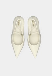 Escarpins pointus de couleur crème en matériau synthétique lisse. Caractérisés par un design élégant avec un logo blanc subtil à l'intérieur.