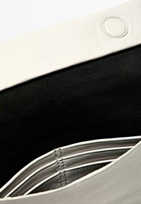 Borsa in pelle con esterno bianco e interno in suede nero, dotata di scomparti multipli e dettagli di cucitura ordinati. La chiusura è un bottone a pressione rotondo.