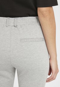 Pantalons de survêtement gris avec une taille élastique, une poche arrière et un tissu doux et texturé pour le confort. Aucune ornementation supplémentaire visible.