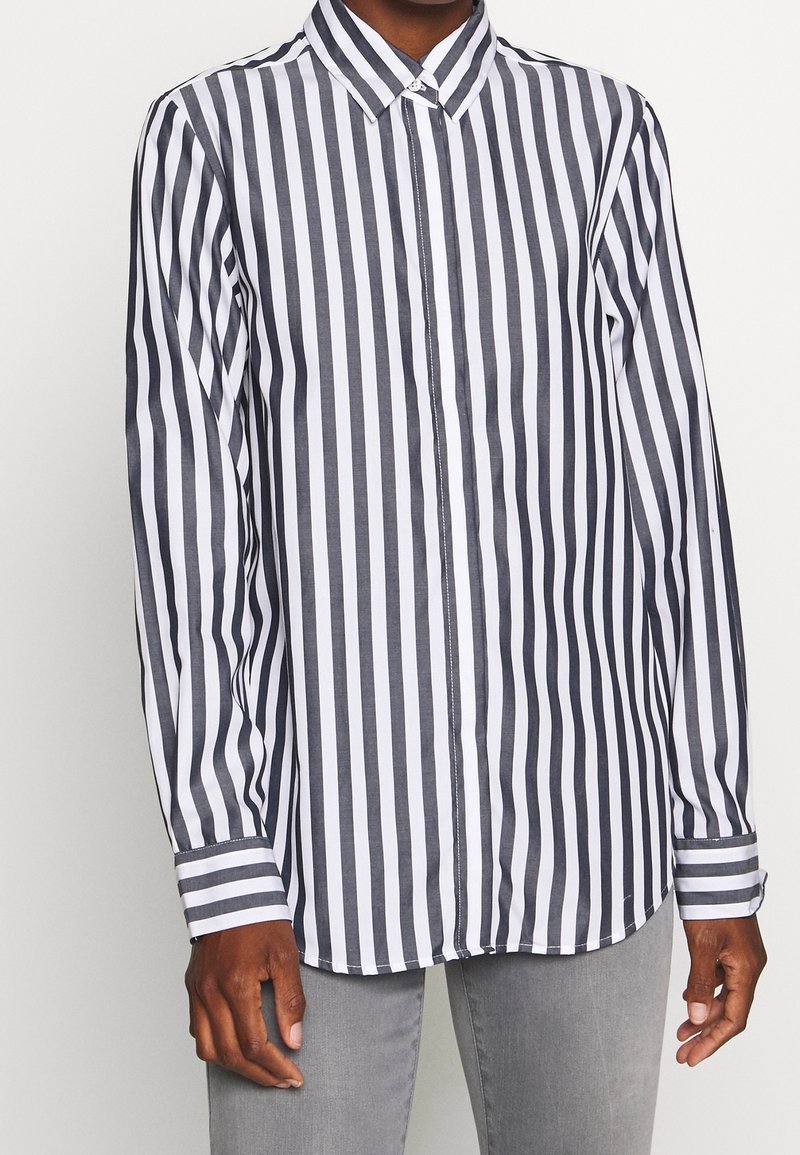 Skjorta med lång ärm, knäppning framtill och vertikala marinblå och vita ränder, i en blandning av bomull, med krage och enkel knapp på ärmsluten.
