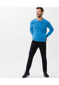 Light blue knit sweater with a round neckline, paired with black slim-fit pants and navy shoes, featuring a classic design and soft texture.
