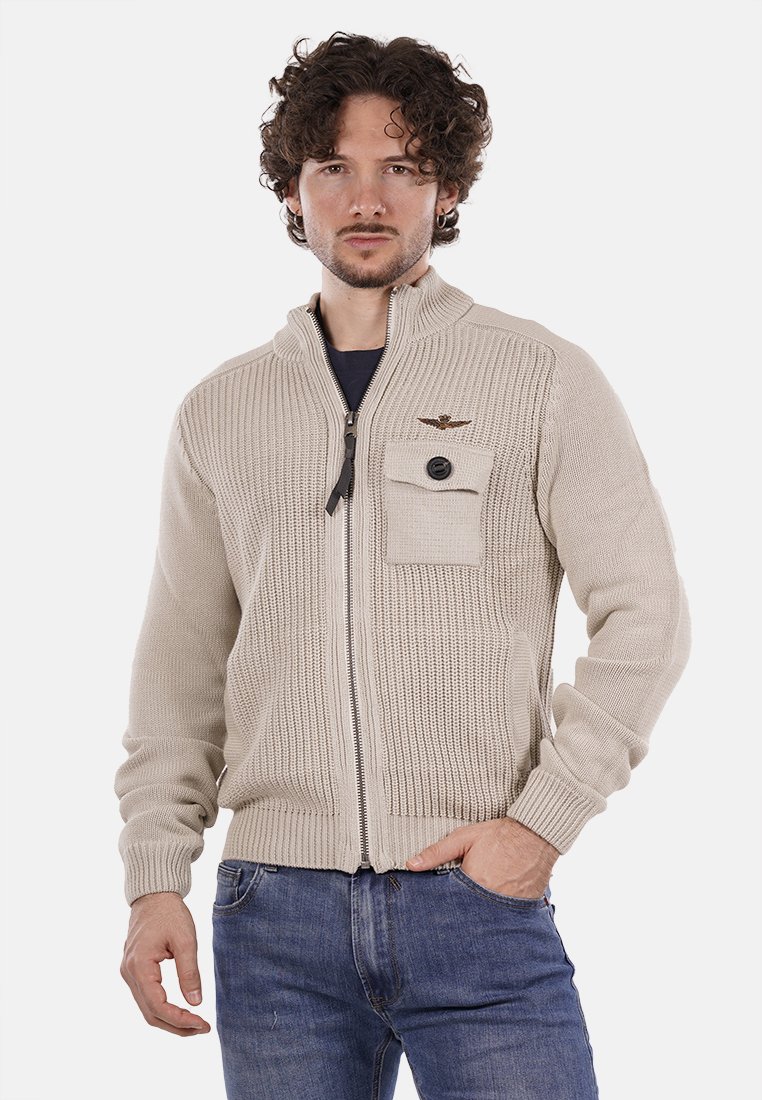 Maglione beige con zip, in maglia testurizzata, con polsini a coste e una tasca sul petto con un bottone decorativo e un accento del logo.