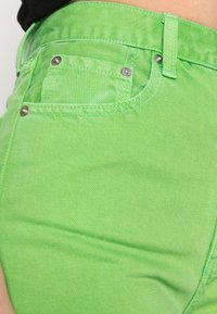 Pantalones cortos de mezclilla verdes con una textura suave, diseño de cinco bolsillos, detalles de herrajes metálicos y costuras contrastantes.