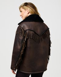 Veste en cuir brun avec un col en fausse fourrure noire, présentant des franges le long des bras et dans le dos, une texture travaillée et des boutons ronds.