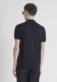 Marineblauwe polo met korte mouwen van een zachte gebreide stof, met een geribde kraag en manchetten, een rechte zoom en een minimalistisch ontwerp.