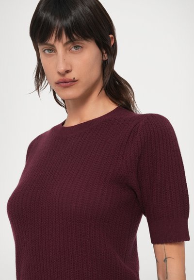 Bordó rövid ujjú pulóver texturált kötött mintával, kerek nyakkivágással és enyhe puffos vállvarrással. Puha anyag bordázott mandzsettákkal.