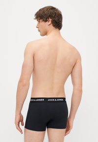 Svart bomull boksershorts med en hvit "JACK & JONES" logo på linningen, tettsittende design og glatt tekstur, vist fra baksiden.