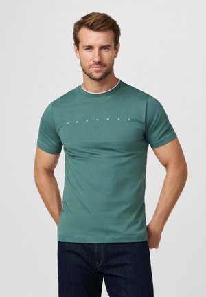 Camiseta de algodón verde con cuello redondo, con el texto blanco "HACKETT" en el pecho. Manga corta, textura suave, estilo ajustado.
