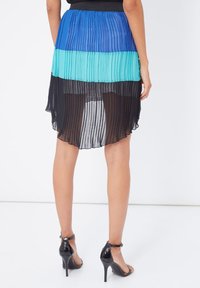 Falda plisada con cuatro bloques de color horizontales: azul, turquesa, negro y negro semitransparente. El material es ligero y fluido, con un dobladillo curvado.