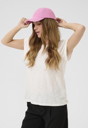 Bela teksturirana majica s kratkimi rokavi, kombinirana z roza baseball kapo. Kapa ima ukrivljen rob, ki poudarja sproščen videz.