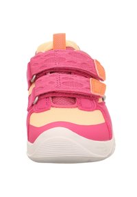 Baskets de sport roses et jaunes avec deux bandoulières Velcro, en tissu texturé, à bout arrondi et semelle profilée. Les accents comprennent des détails oranges.