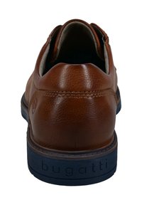 Braunes Leder-Schuh mit strukturierten Oberflächen, abgerundetem Absatz und einer marineblauen Gummisohle. Mit einem eingestanzten Logo auf dem Absatz und einem gepolsterten Innenraum.