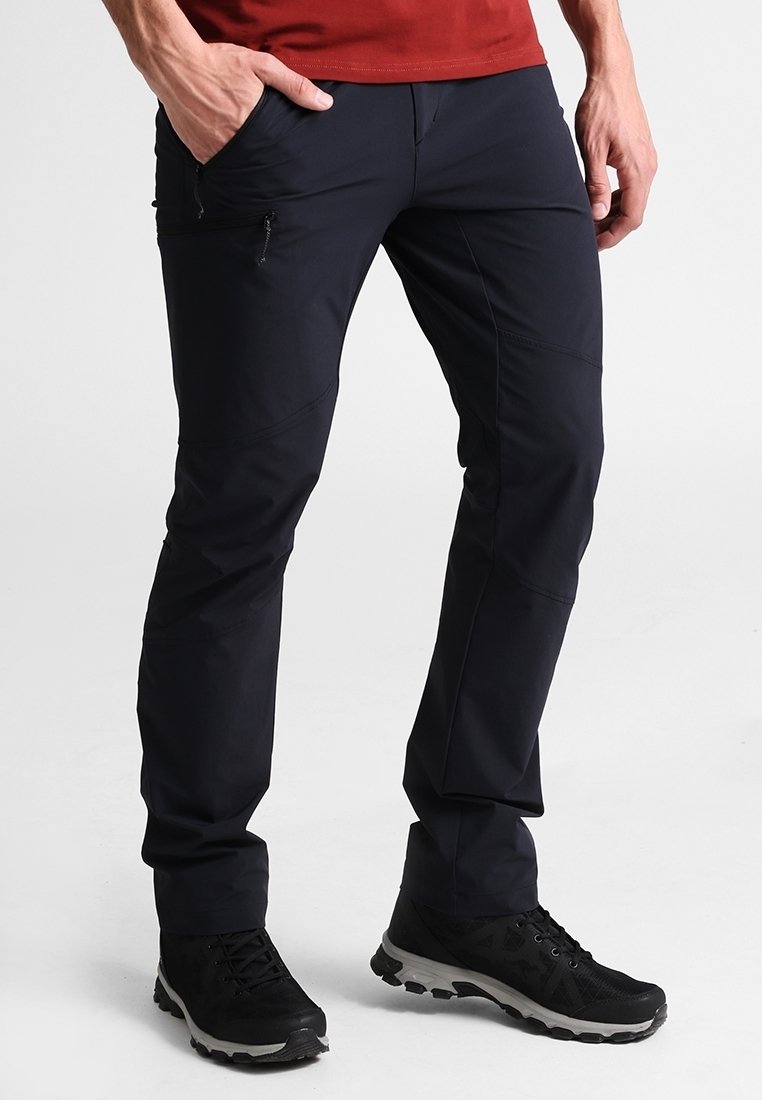 Navyblå lätta byxor med en slim fit, dragkedjefickor och knäutsprungsömmar, kombinerat med svarta träningsskor.