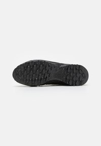 Svart idrettssko såle med en teksturert, robust design og et heksagonalt mønster for godt grep. Holdbart gummimateriale.
