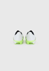 Botas de fútbol blancas con un patrón texturizado, acentos negros y suelas de un brillante color verde. Diseño ligeramente cónico, presentan tachuelas redondas para mayor tracción.