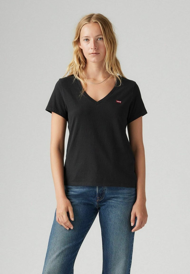 Camiseta negra de cuello en V hecha de algodón con mangas cortas. Presenta un pequeño logo rojo de Levi's en el lado izquierdo del pecho, adecuada para uso casual.