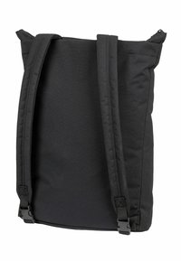 Mochila de tela negra con correas ajustables, forma rectangular, superficie texturada y diseño minimalista. Cierre superior con cremallera.