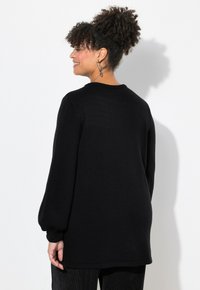 Schwarzer Strickpullover mit langen, puffartigen Ärmeln und rundem Ausschnitt. Glatte Textur, lässige Passform und ein schlichtes Design.