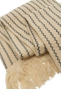 Beige vevet skjerf med svarte skråstriper og frynser i kantene. Myk tekstur med lett design som passer til lagdeling.