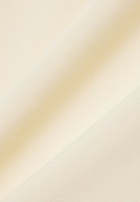 Textuurige crèmekleurige stof met een geweven patroon, die een gladde afwerking en een zachte val toont, ideaal voor diverse textieltoepassingen.