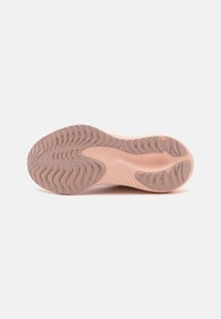 Sole of a sneaker, featuring a light pink rubber material with a zigzag pattern for traction and a smooth central area for flexibility.