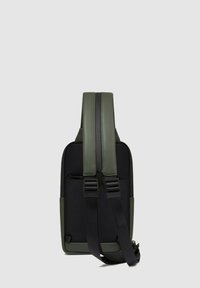 Mochila con un esquema de colores verde y negro, fabricada con tela texturizada, con un diseño elegante y correas ajustables. Compartimentos con cremallera visibles.